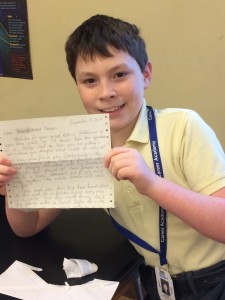 Boy in yellow polo shirt smiling and holding a letter
